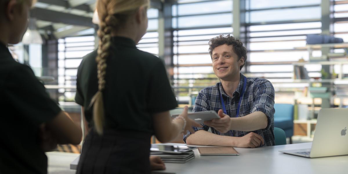 Ein Lehrer nimmt iPads von Schüler:innen entgegen