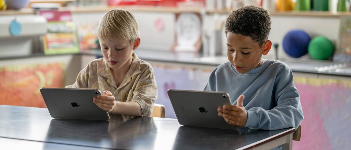 Zwei Schüler arbeiten in einem Klassenraum einer Volksschule mit je einem iPad
