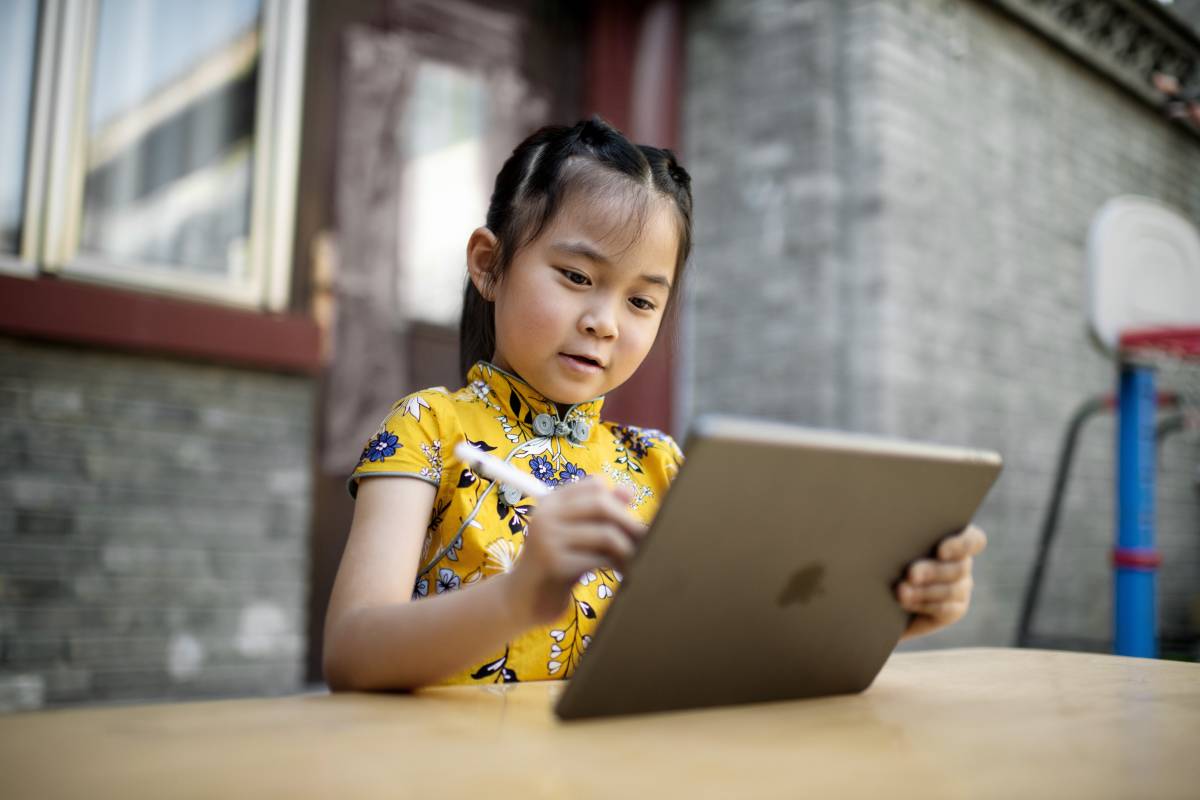 Eine Schülerin im Volksschulalter schreibt mit dem Apple Pencil auf einem iPad