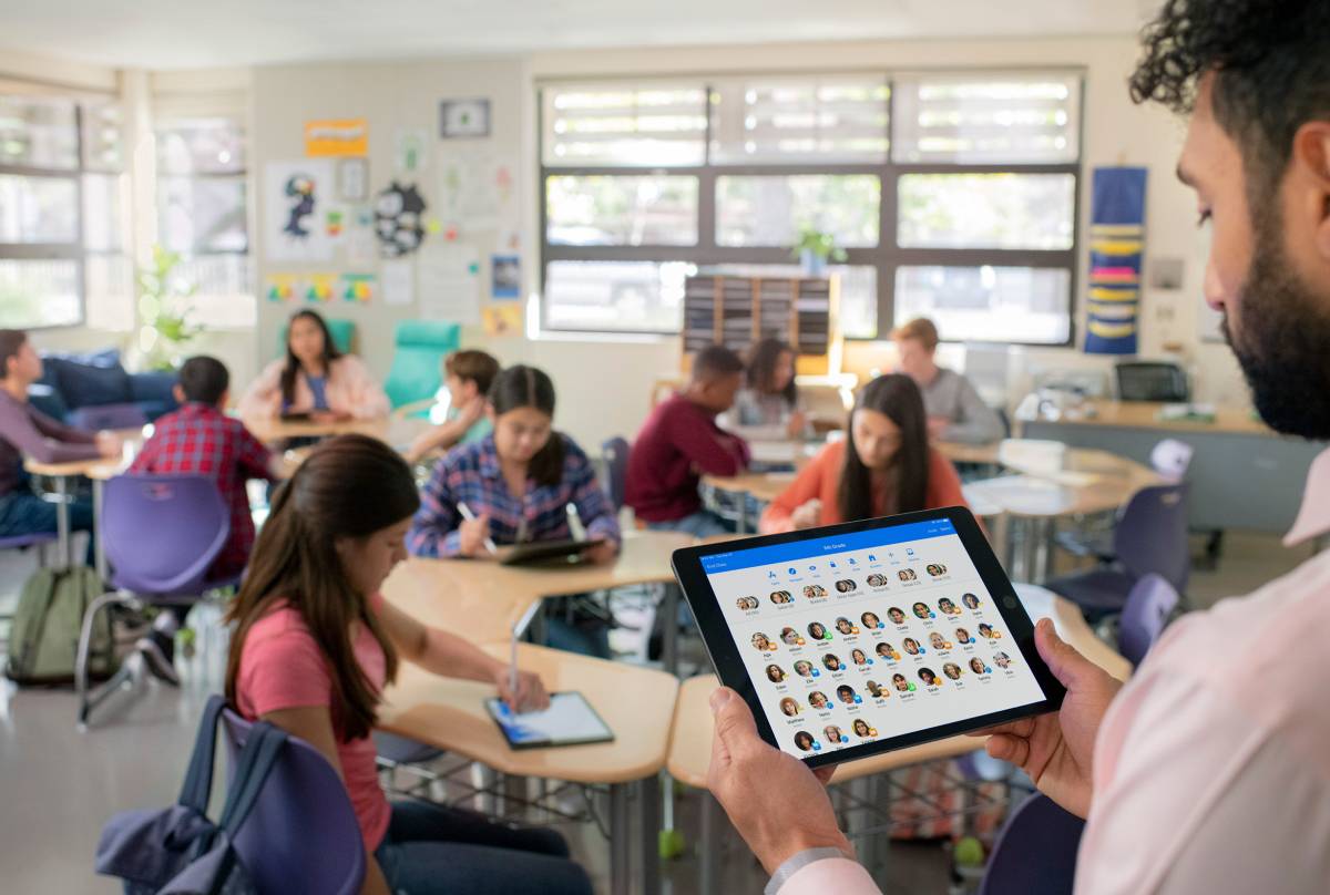 Ein Lehrer bedient in einer Klasse ein iPad mit der Classroom App