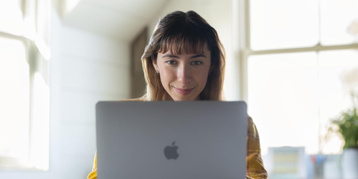 Die Mitarbeiterin einer Bildungseinrichtung arbeitet mit einem MacBook – dafür besteht die Möglichkeit der Anschaffung über das Tools at Work Abo-Modell