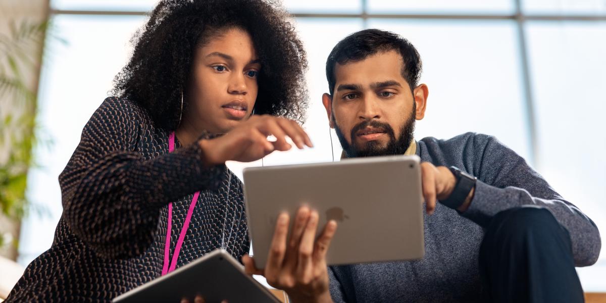 Eine Trainerin und ein Lehrer befassen sich mit einer Aufgabenstellung am iPad